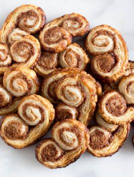 These cinnamon sugar palmiers are ready in under 20 minutes and are sure to please everyone. Perfectly sweet, crunchy and made with store bought puff pastry. You'll love these cookies!