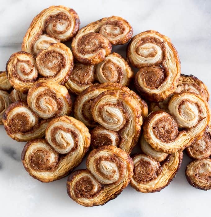 These cinnamon sugar palmiers are ready in under 20 minutes and are sure to please everyone. Perfectly sweet, crunchy and made with store bought puff pastry. You'll love these cookies!
