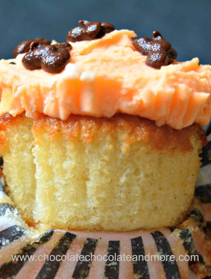 a yellow cupcake topped with orange buttercream frosting