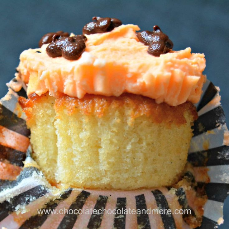 a yellow cupcake topped with orange buttercream frosting