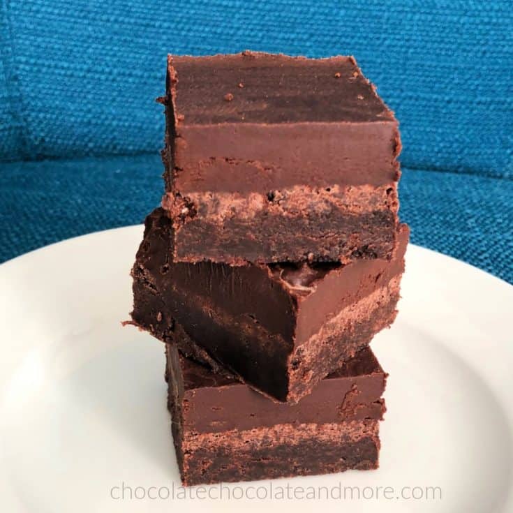 a stack of three chocolate truffle bars on a white plate with a blue background. Each bar has three separate layers of chocolate.