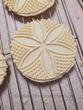Round flat cookies with decorative imprints cooling on a wire rack.