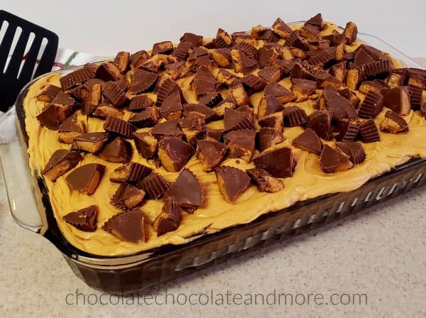 Triple Frosted Peanut Butter Cup Sheet Cake A rectangular pan of cake covered with peanut butter frosting and cut up peanut butter cups.
