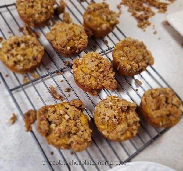several sweet potato praline muffins cooling on a baking rack. crumbles of praline topping are under the racks