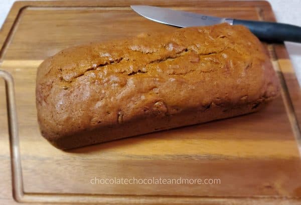 a whole loaf of pumpkin bread on a wooden cutting board with a knife