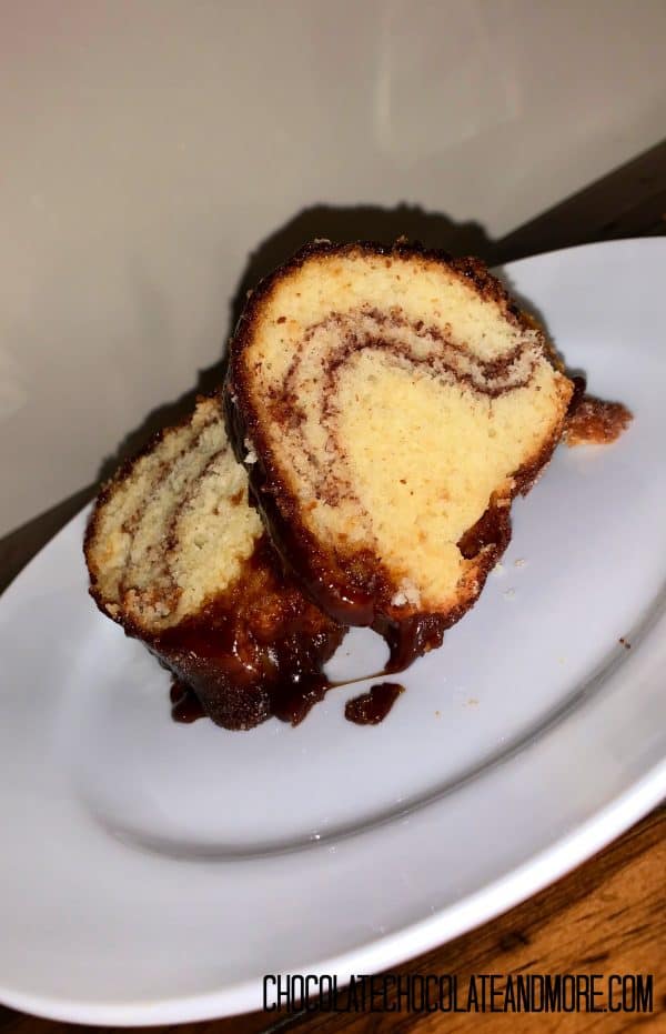 2 slices of Monkey Bread Cake sitting on a circular white plate on a wooden table in front of an off-white background.