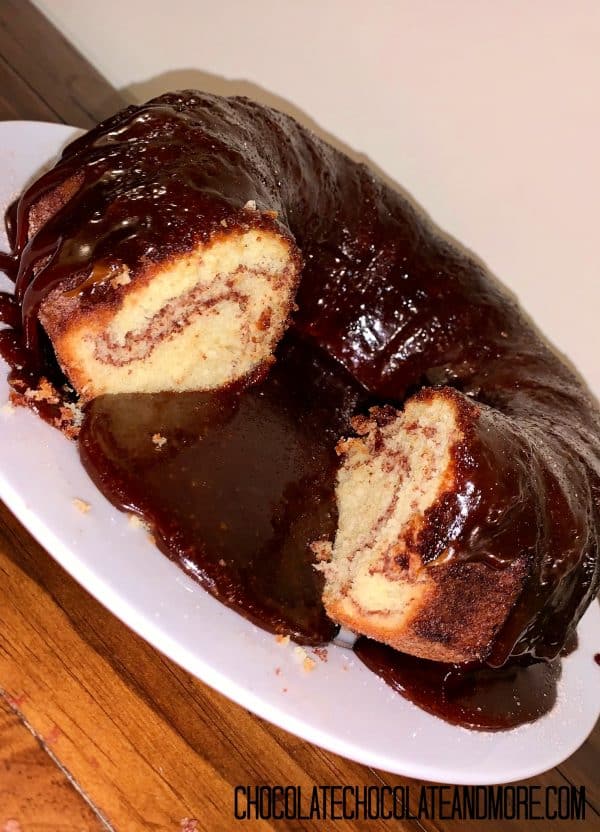 Monkey Bread Cake with 2 slices cut out sitting on a circular white plate on a wood table in front of an off-white background
