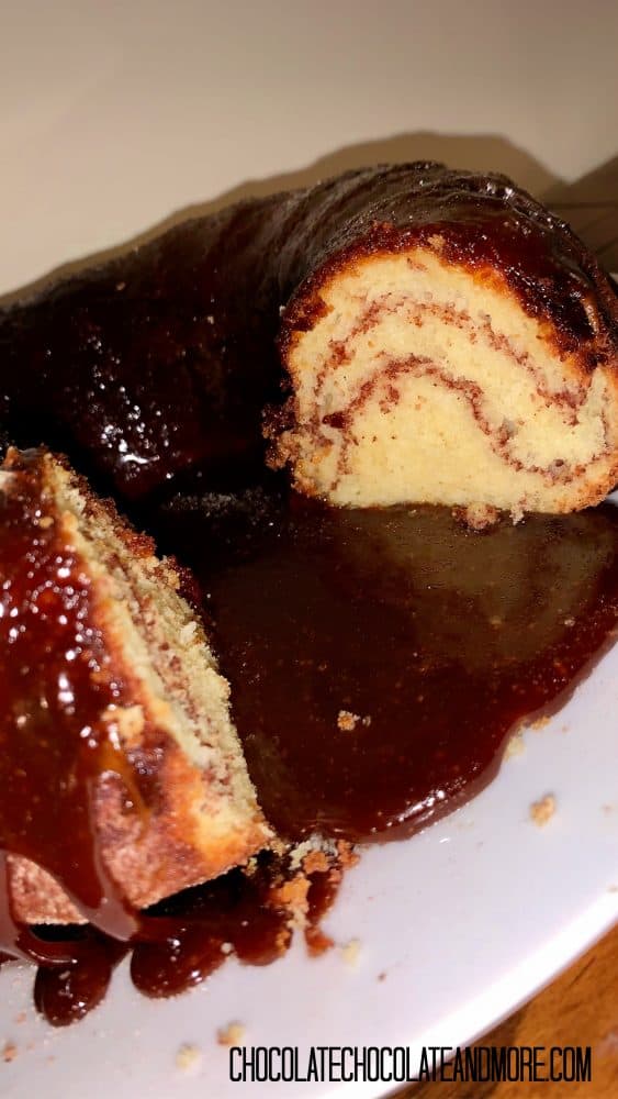 Monkey Bread Cake with 2 slices cut out sitting on a circular white plate on a wood table in front of an off-white backgorund.