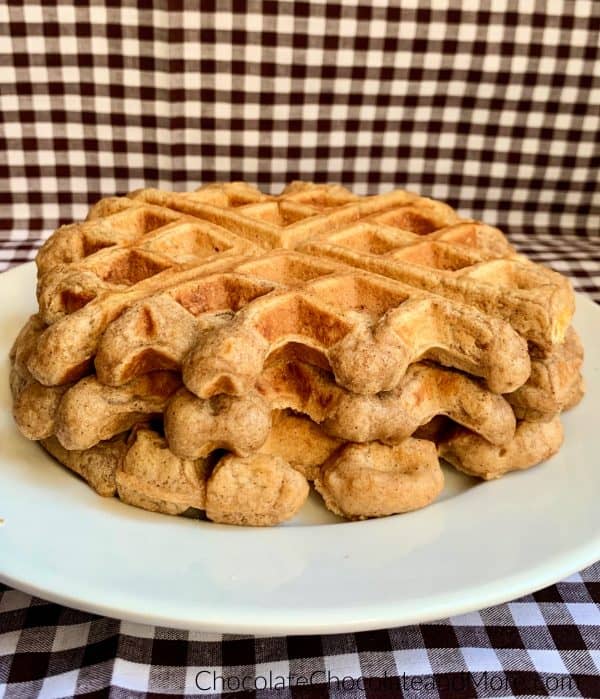 Cinnamon Applesauce Waffles sitting on a white circular plate and a white and black checkered background.