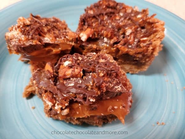 three sliced bars sitting on a blue plate oozing with caramel