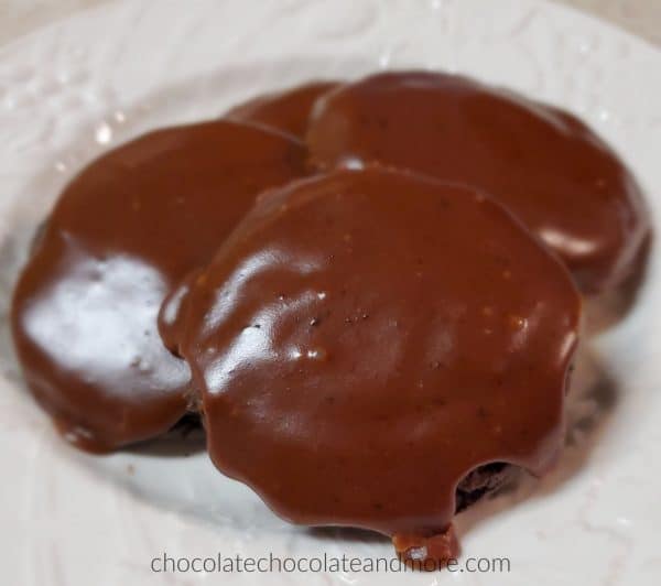 three chocolate iced cookies on a white plate