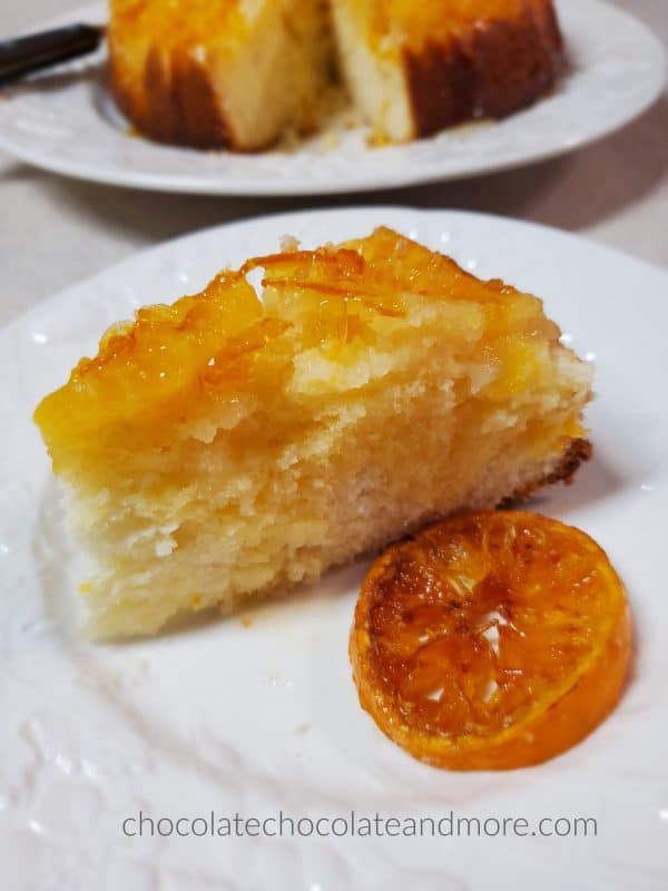 a slice of mandarin upside down cake on a plate with a slice of candied orange 