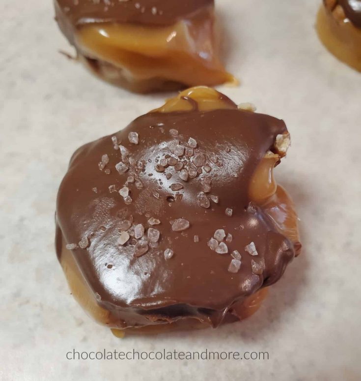roasted pecans covered with caramel and chocolate. there are sea salt crystals on top