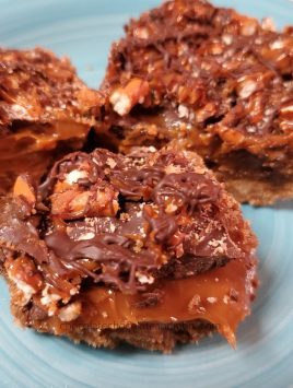 three chocolate caramel pretzel bars on a blue plate