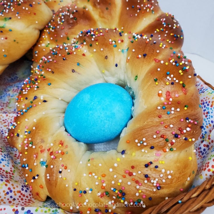 A twisted Italian Easter Bread covered in colorful sprinkles and a blue Easter egg.