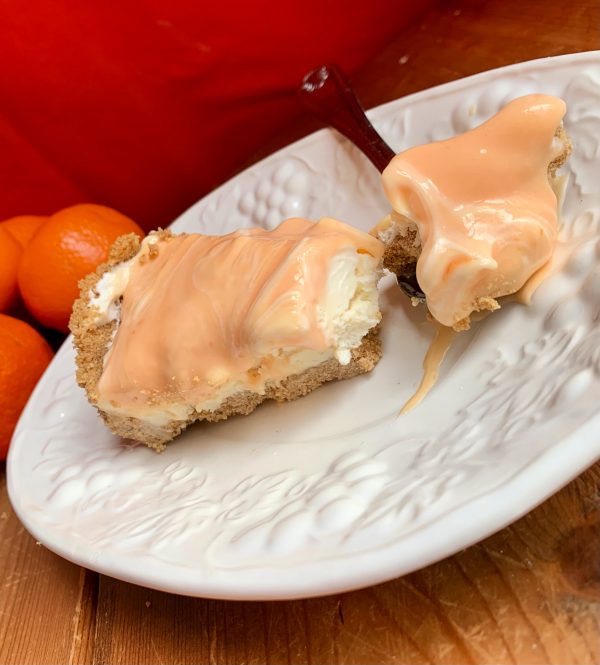 2 slices of Orange Creamsicle Swirl Cheesecake in front of a red background.