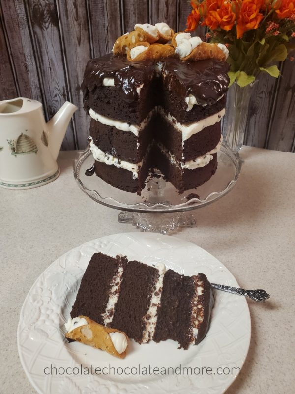 a huge triple layer chocolate cake. In front is a slice that has been cut out to show the layers.