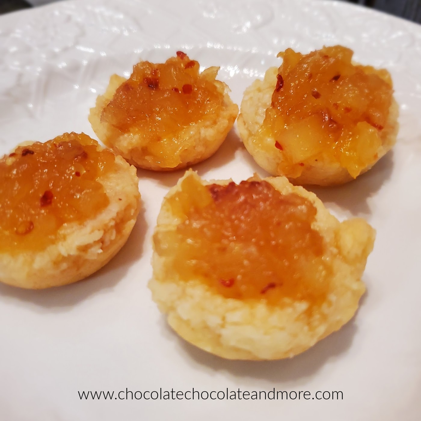 four muffins on a white plate topped with spiced pineapple