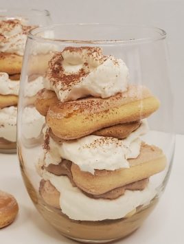 clear glass filled with layers of whipped coffee tiramisu and lady fingers