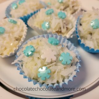 several coconut covered snowballs on a plate with blue and white snowflake sprinkles