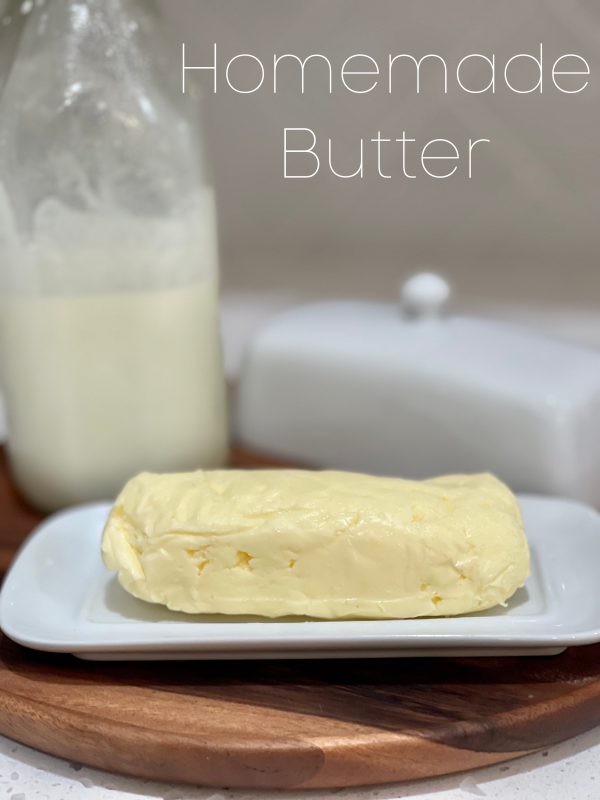 Homemade Butter on a butter dish with buttermilk in a milk jug sitting behind it.