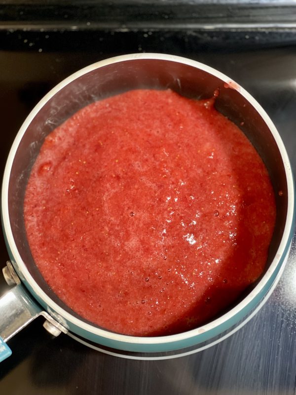 Pureed strawberries before they are reduced in a saucepan on the stove.