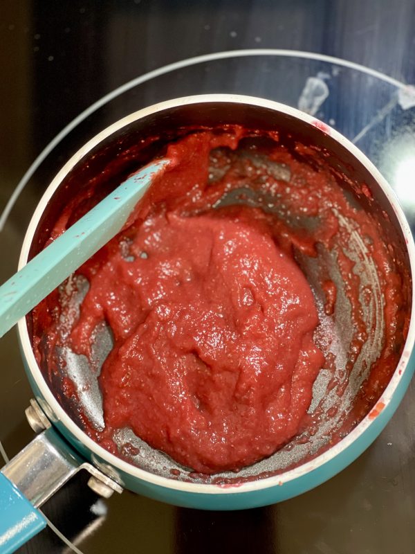 Reduced strawberries in a saucepan on the stove.