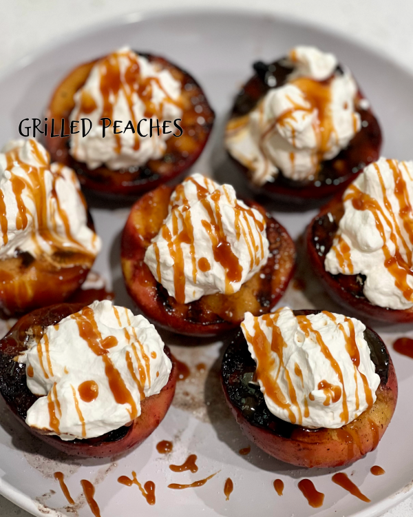 Grilled Peaches topped with whipped cream and caramel sauce on a white plate