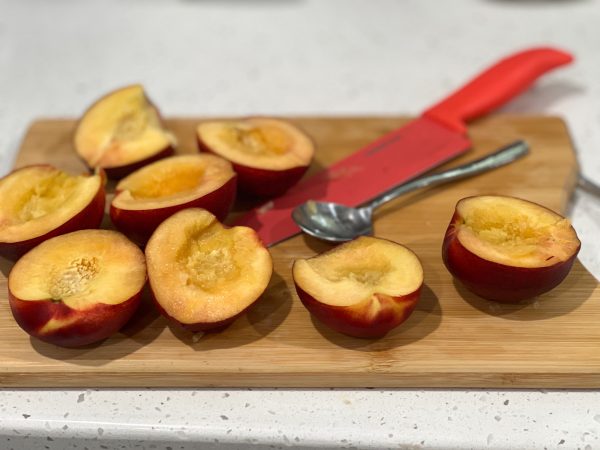 peaches halved and pitted on a cutting board