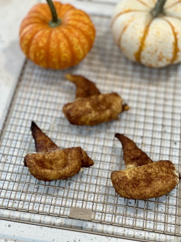 Cheesecake Stuffed Witch Hats on a cooling rack with 2 pumpkins