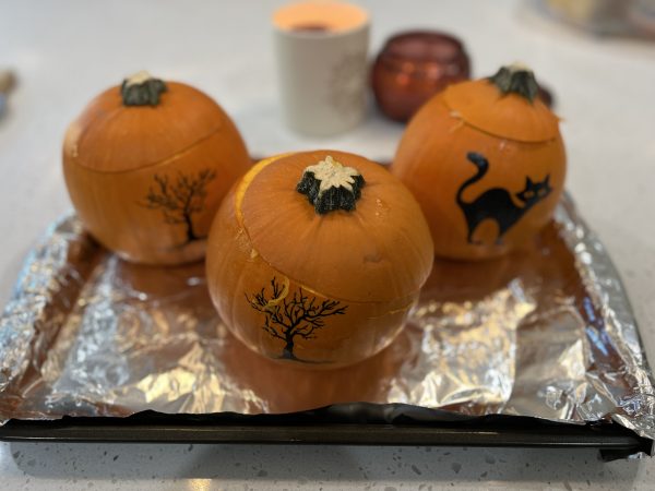 3 pumpkins sitting on a baking sheet lined with aluminum foil