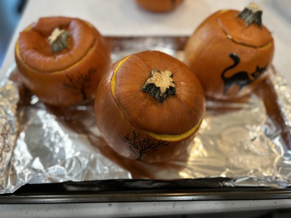 3 pumpkins after coming out the oven sitting on a baking sheet lined with aluminum foil 