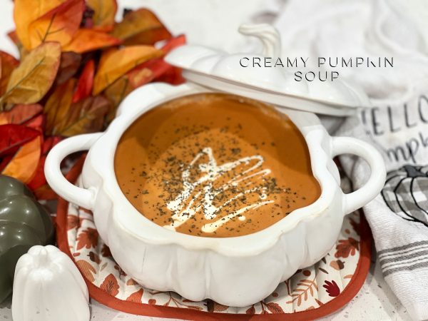 Creamy Pumpkin Soup in a pumpkin shaped baker on a fall themed pot holder 