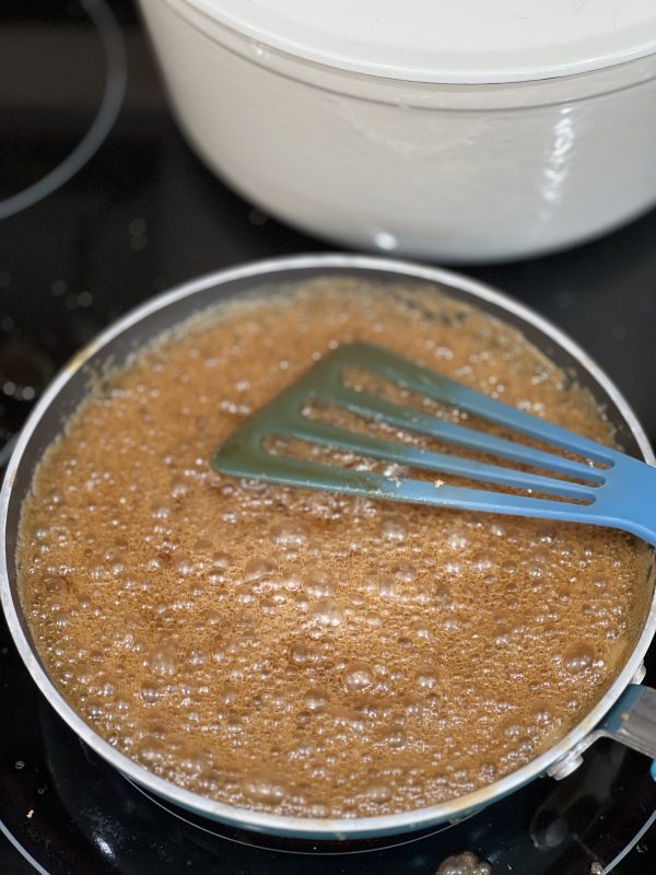 the glaze for Boozy Bourbon Cornbread in a skillet on the stove