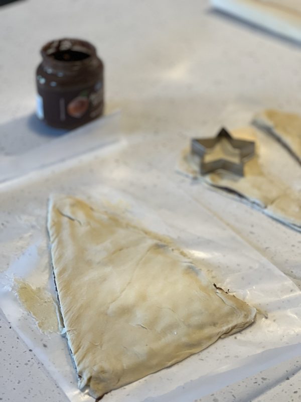 Tear & Share Crescent Christmas Tree  dough cut into a triangle and the star cookie cutter cutting a star out the the cut off dough