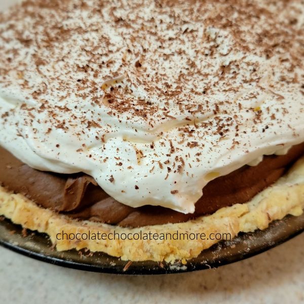 a close up view of chocolate pie topped with whipped cream and chocolate shavings