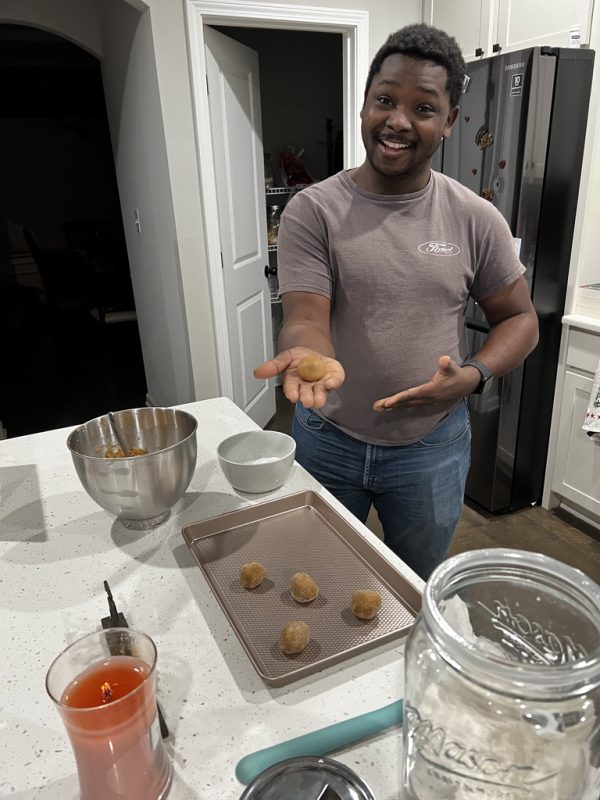 kal rolling the dough into balls and placing them on a cookie sheet